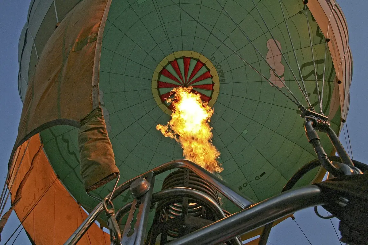 Looking up into a hot-air balloon from below, with a big yellow flame from the burner heating the air inside