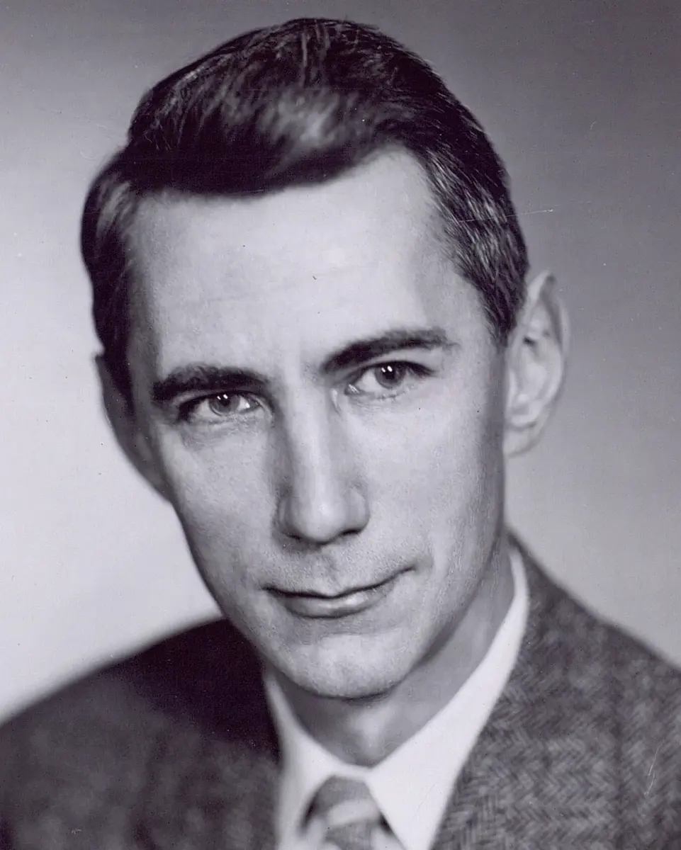 A black-and-white portrait of a man in a jacket and tie