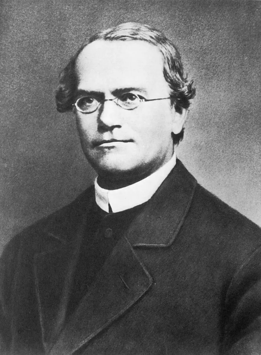 A black and white portrait of a man with round glasses in a dark coat