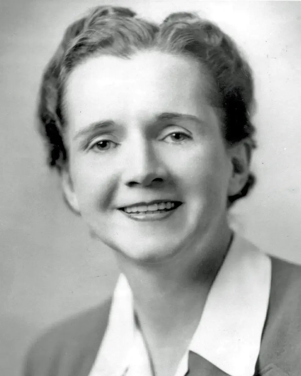 A black-and-white portrait of Rachel Carson, a woman with short wavy hair, smiling slightly