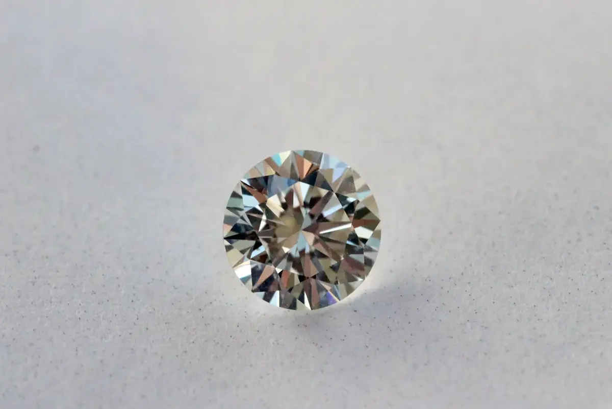 A cut diamond seen from the side, its many faces sparkling with white and colored light