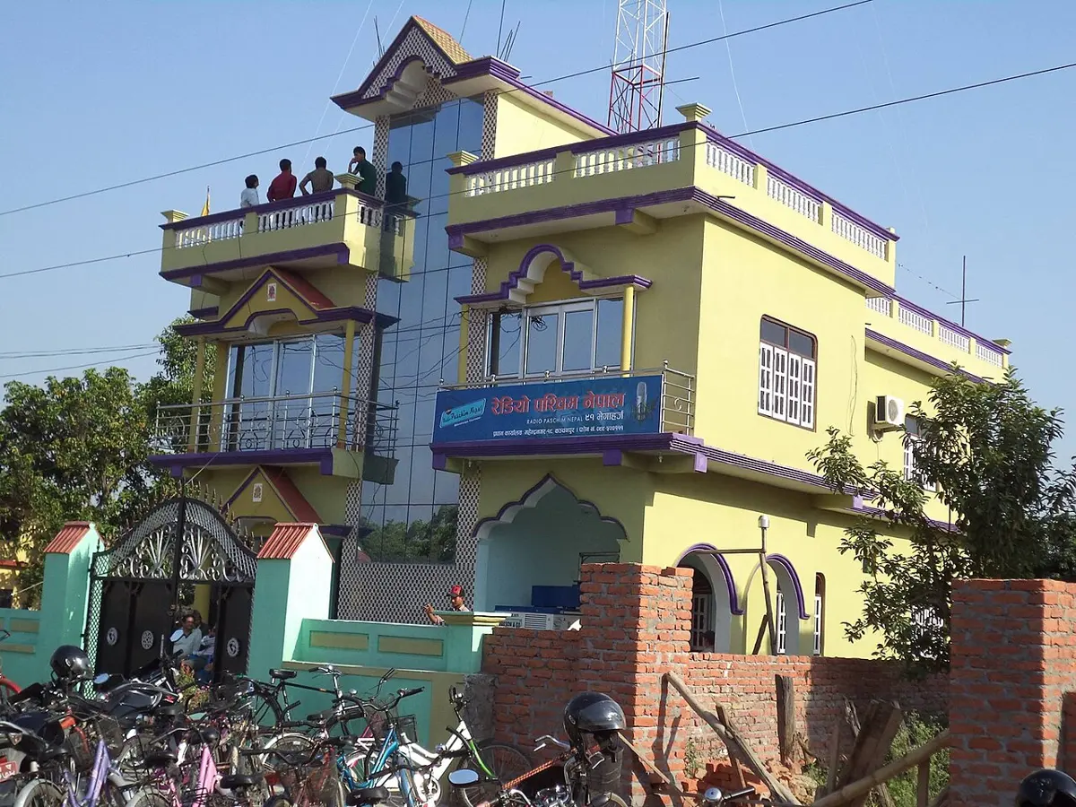 रेडियो पश्चिम नेपालको साइनबोर्ड र छानामा रेडियोको टावर भएको पहेँलो भवन