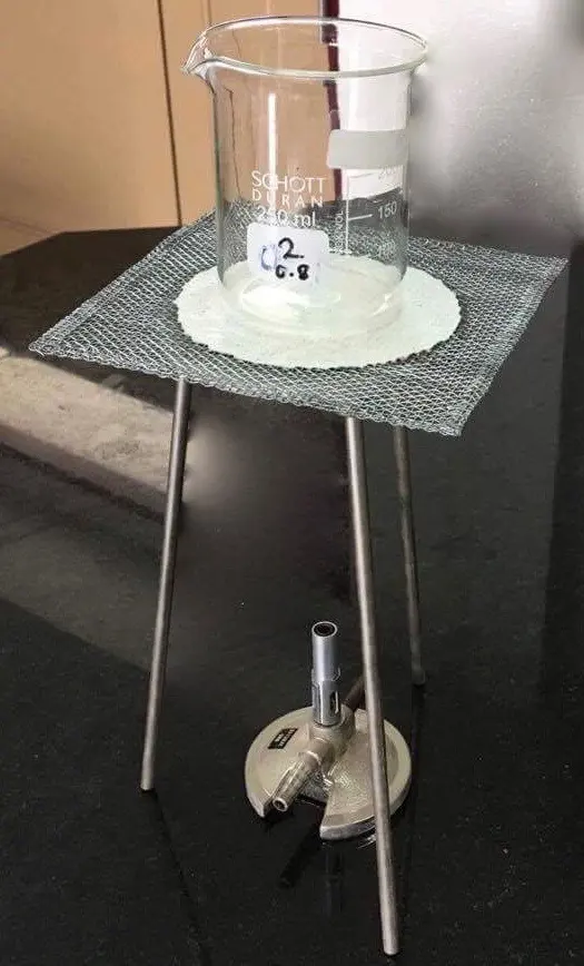 A glass beaker on a square of wire gauze on a metal tripod, with a Bunsen burner under it