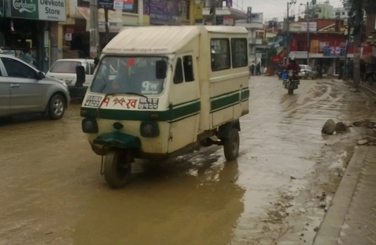 A white three-wheeled electric tempo on a street in Kathmandu