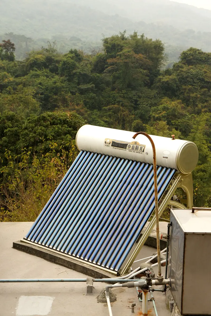 A solar water heater on a flat roof: a row of dark glass tubes tilted towards the sky, joined at the top to a white water tank