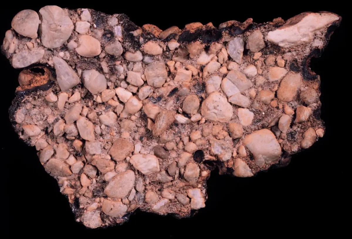A rock made of many rounded pebbles of different colors, set in a finer gray filling
