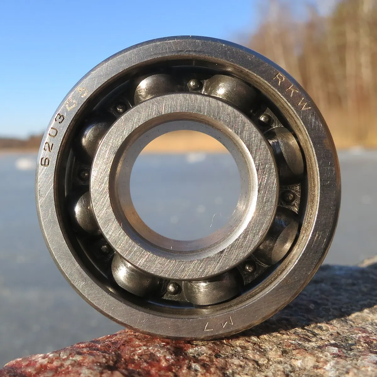 A round steel ball bearing seen face on, with a ring of shiny steel balls between an inner and an outer ring