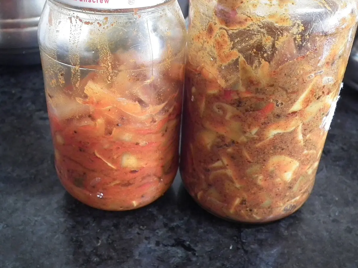 Two glass jars packed with orange-red pickled vegetables