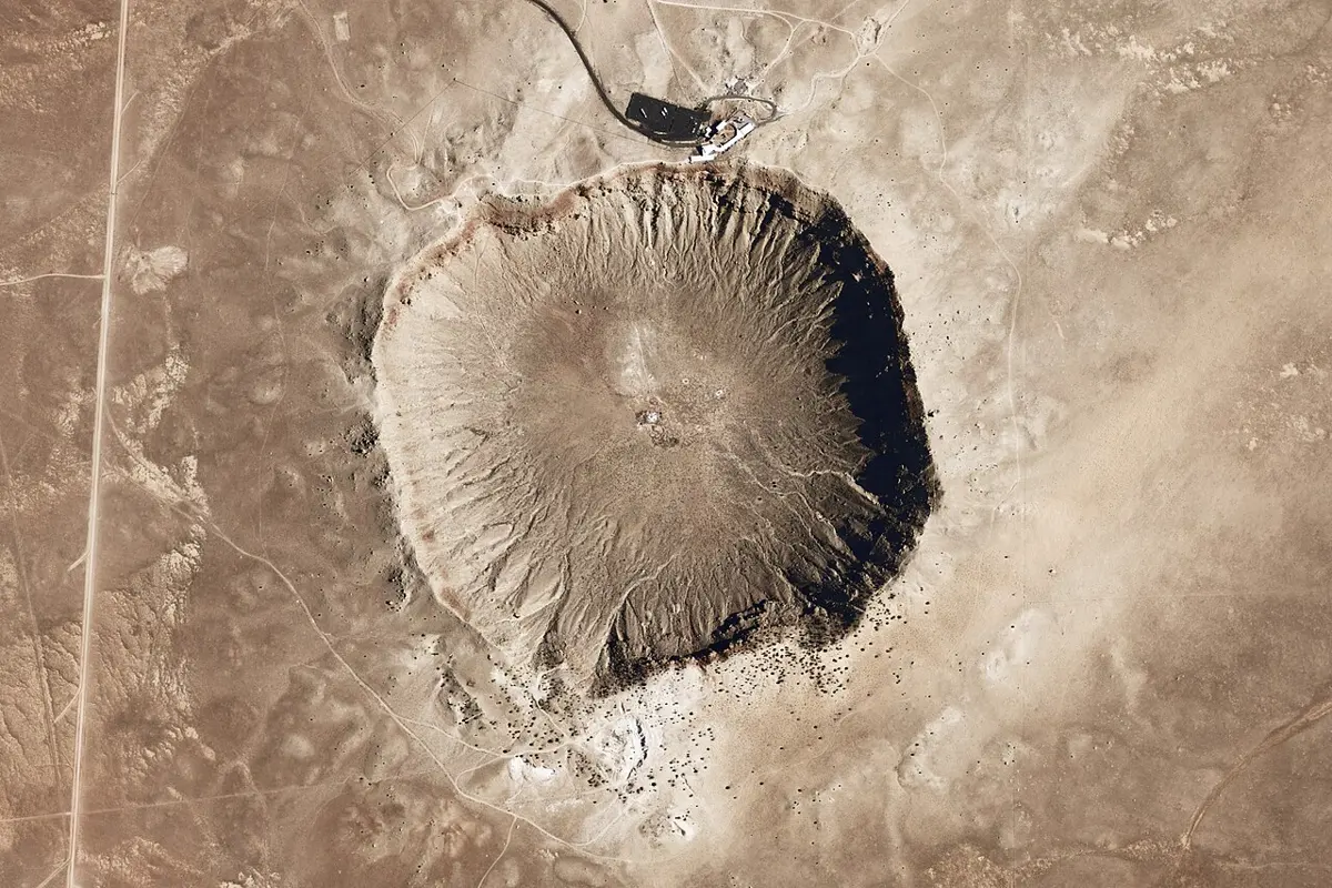 A huge round crater with a raised rim in a flat desert