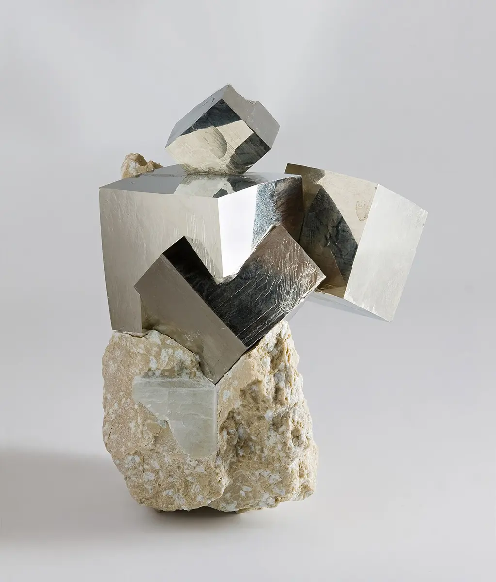 Shiny golden-yellow cubes of pyrite sticking out of gray rock