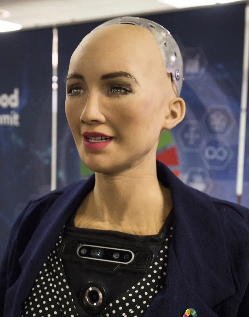 The humanoid robot Sophia, with a human-like face and a see-through back of the head showing machinery