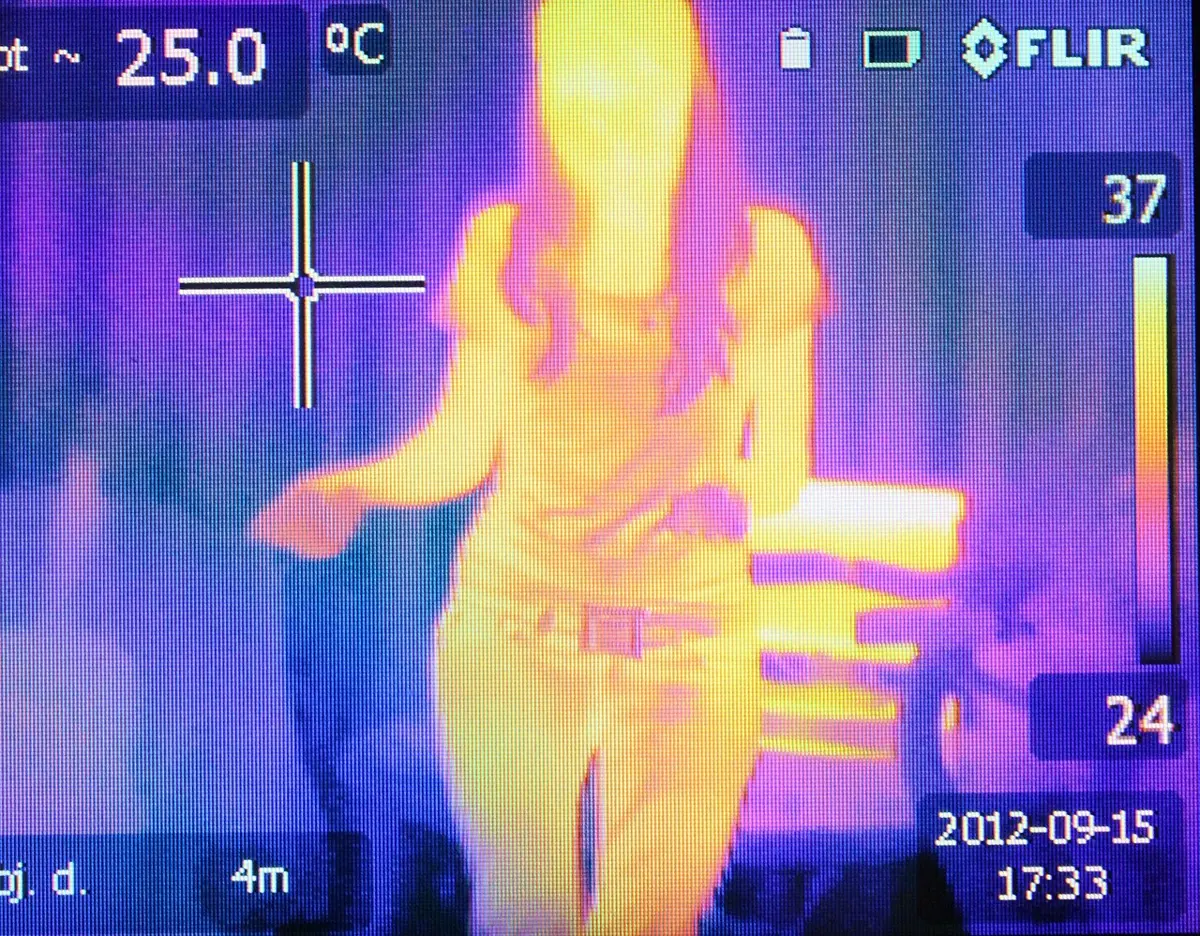A thermal camera picture of a person glowing yellow and orange against a cooler purple background, with a temperature scale from 24 to 37 °C