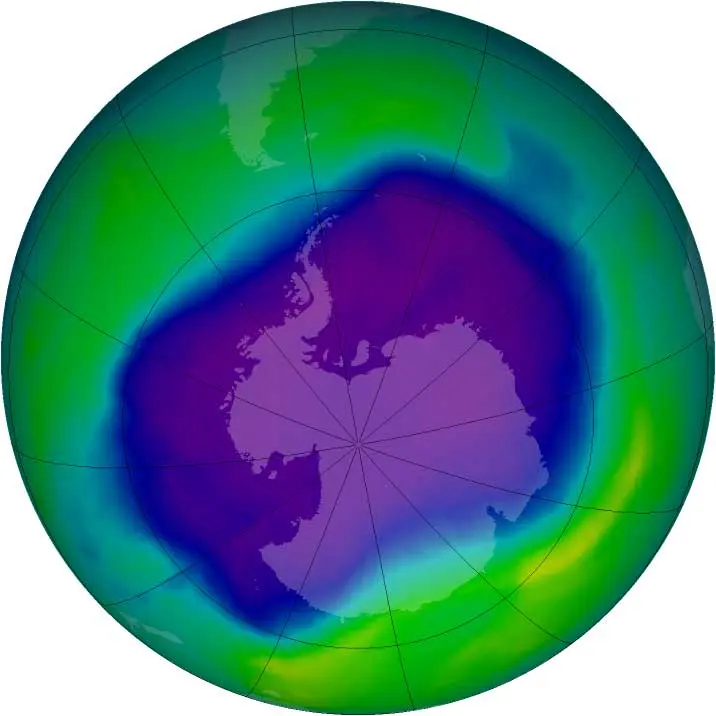 A satellite map of the southern half of the globe, with a large blue and purple patch over Antarctica where the ozone is thin