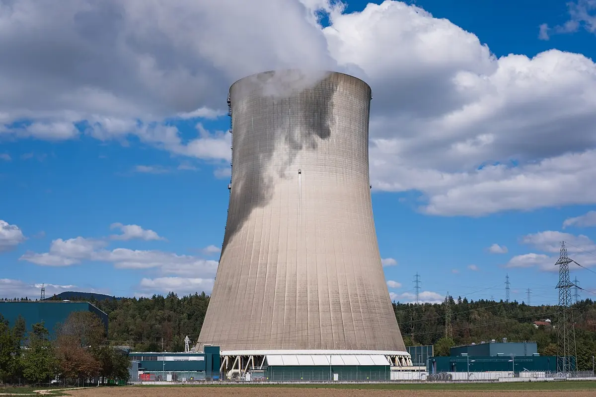 A huge concrete cooling tower, wide at the base and narrower above, with a wisp of vapor at its top