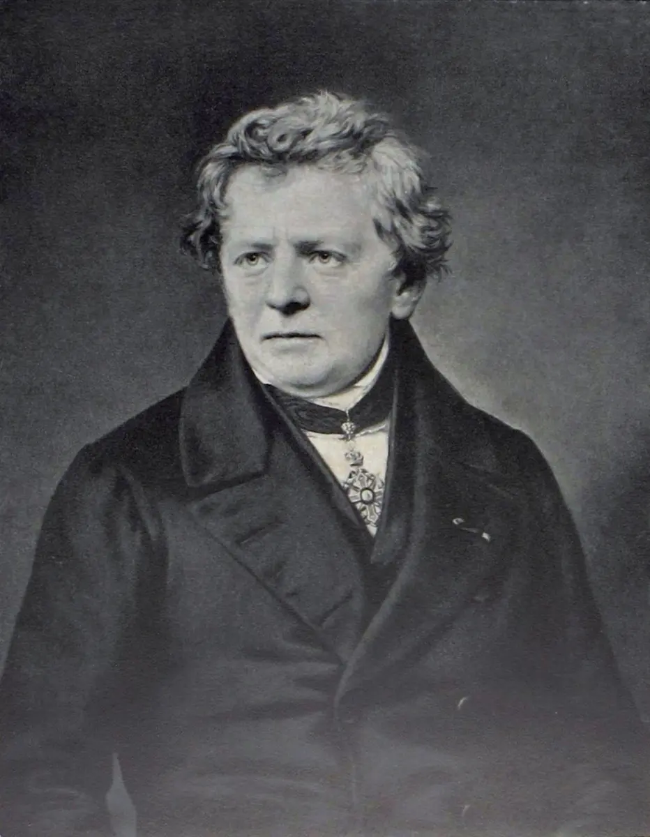 A black-and-white portrait of a man with curly hair in a dark coat and a dark cravat