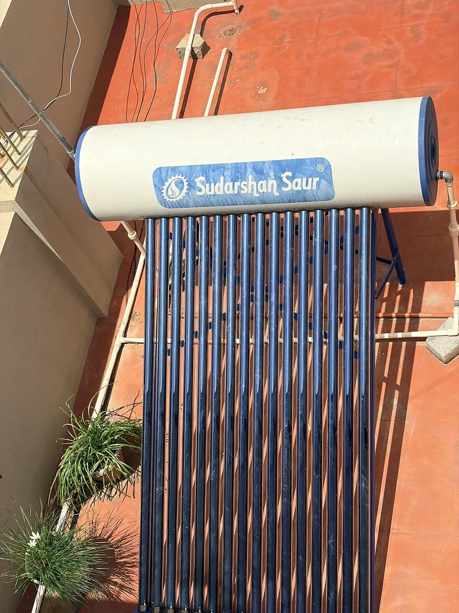 A solar water heater on a flat roof: a row of glass tubes sloping up into a long cylindrical tank on a metal frame