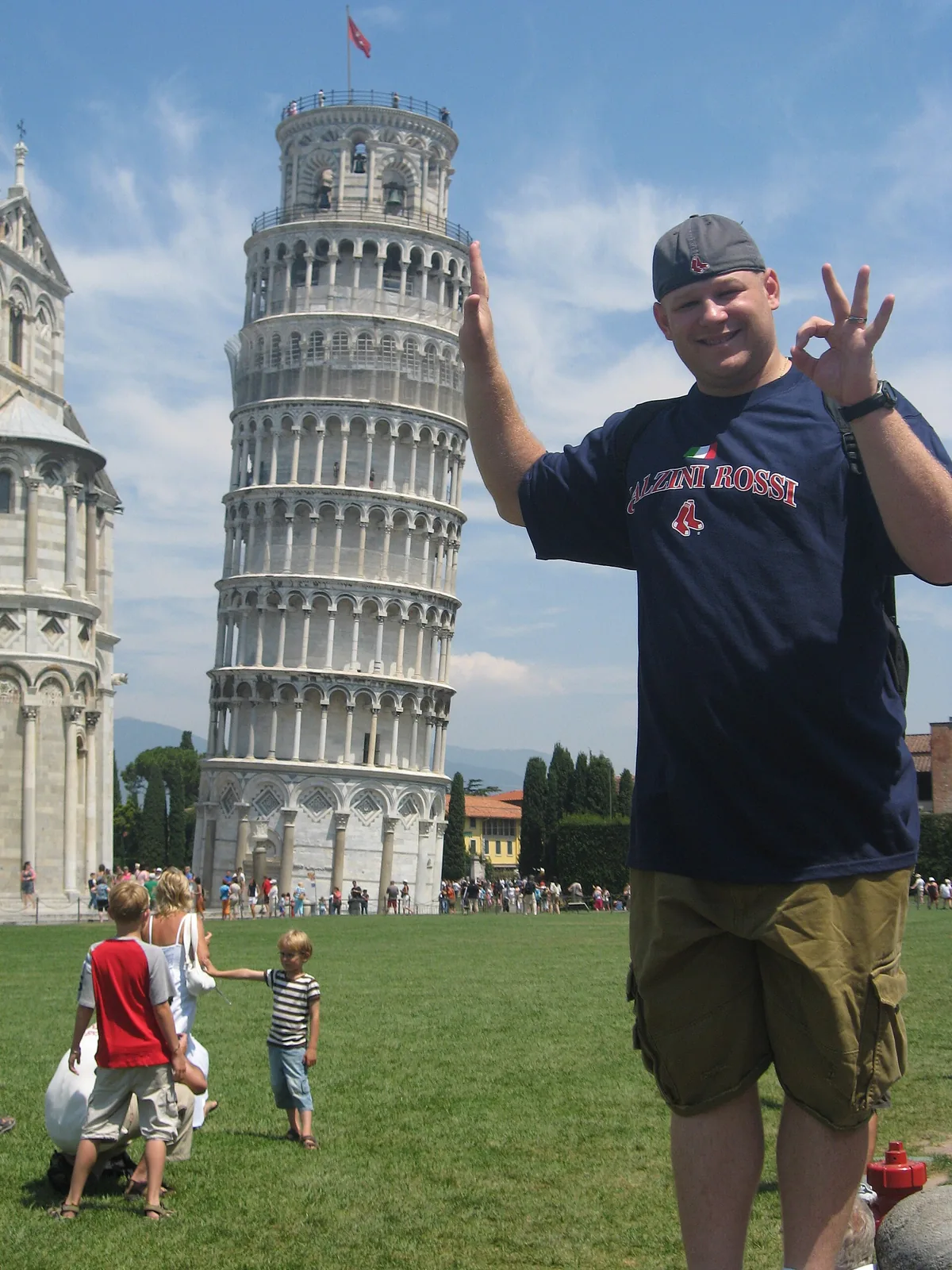 A man in front of the Leaning Tower of Pisa, posing as if holding it up