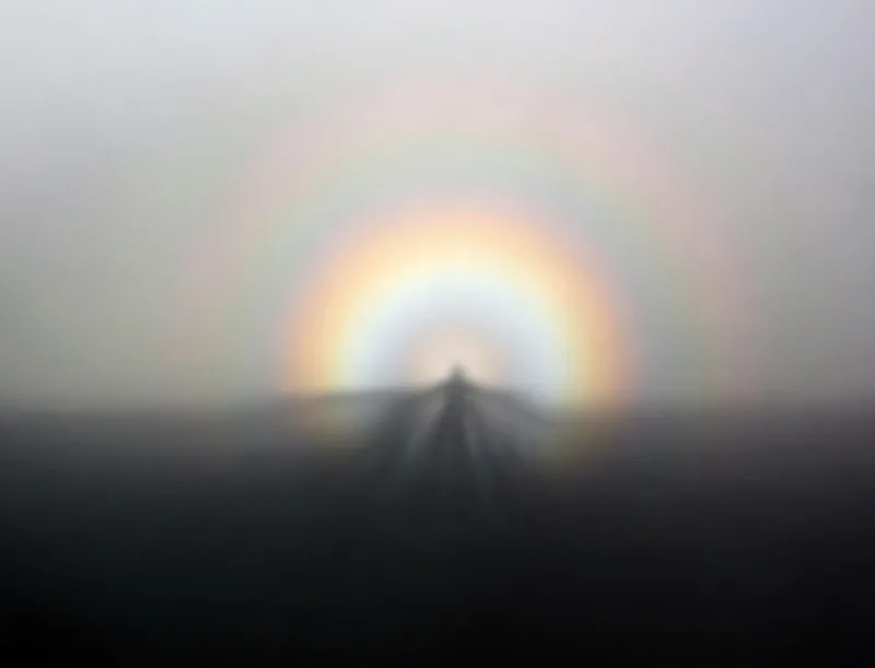 A shadow of a person on the fog, surrounded by a rainbow ring