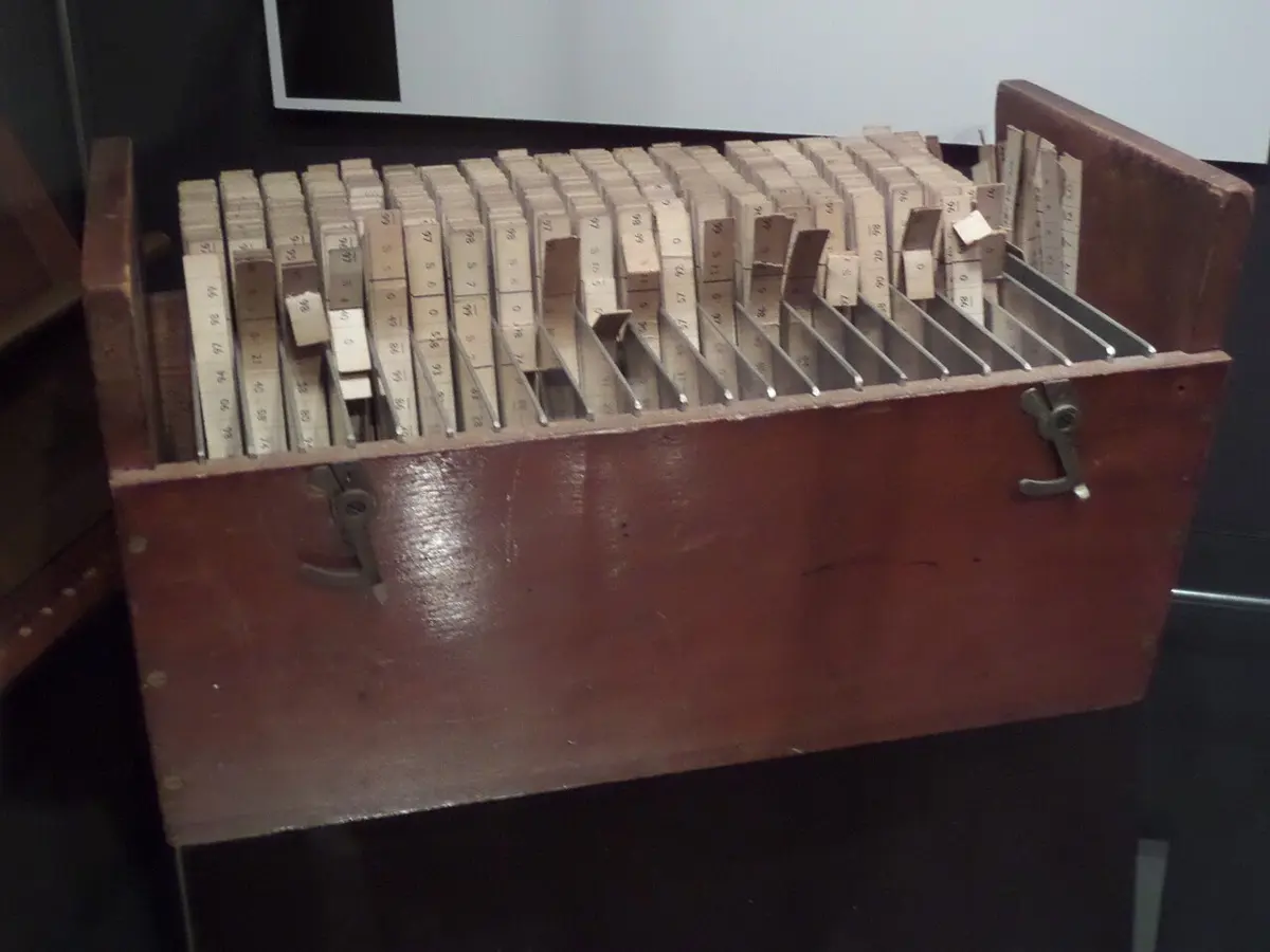 A wooden box packed with many rows of narrow printed cardboard strips standing on edge