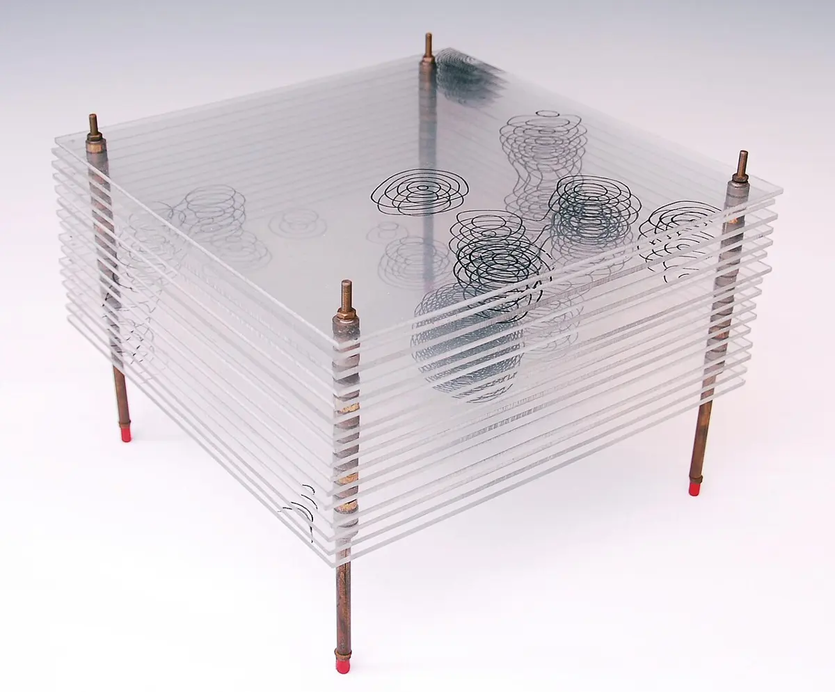 A stack of about a dozen clear glass sheets, held apart by four metal rods. Each sheet has curved contour lines drawn on it, and the contours on the different sheets line up into blobs.