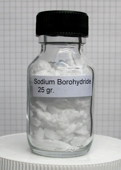 A small glass jar with a black lid, labeled Sodium Borohydride 25 gr., full of white lumps