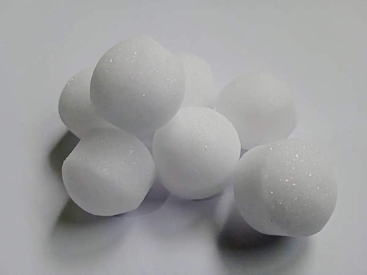 Seven round white balls with a sparkly, crystalline surface, lying on a pale gray surface