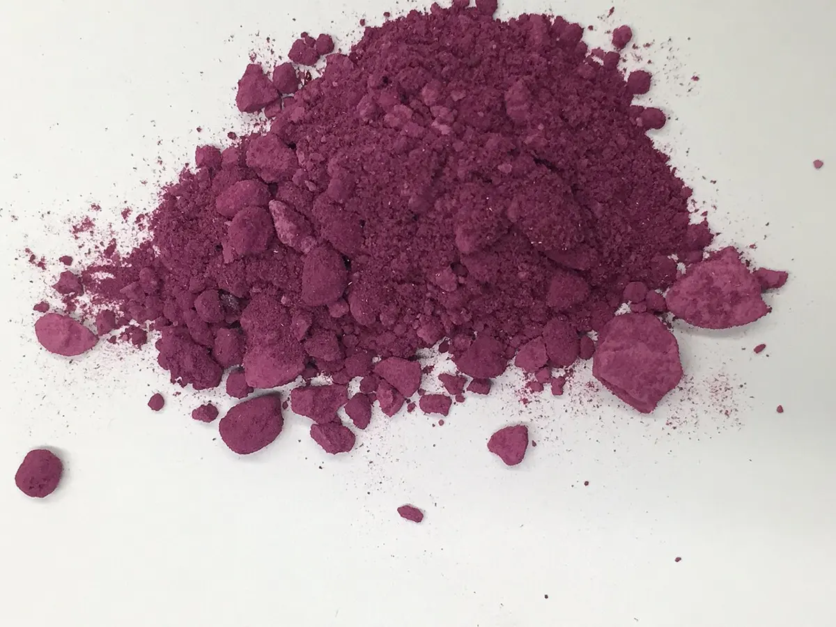 A small heap of fine purple-red powder on a white surface