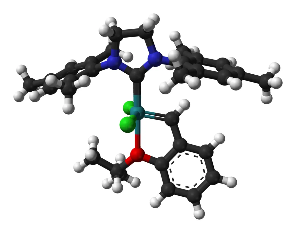 A ball-and-stick model of a molecule: a turquoise metal atom in the center, with two green chlorine atoms, a red oxygen atom, blue nitrogen atoms, and many black carbon and white hydrogen atoms in rings around it