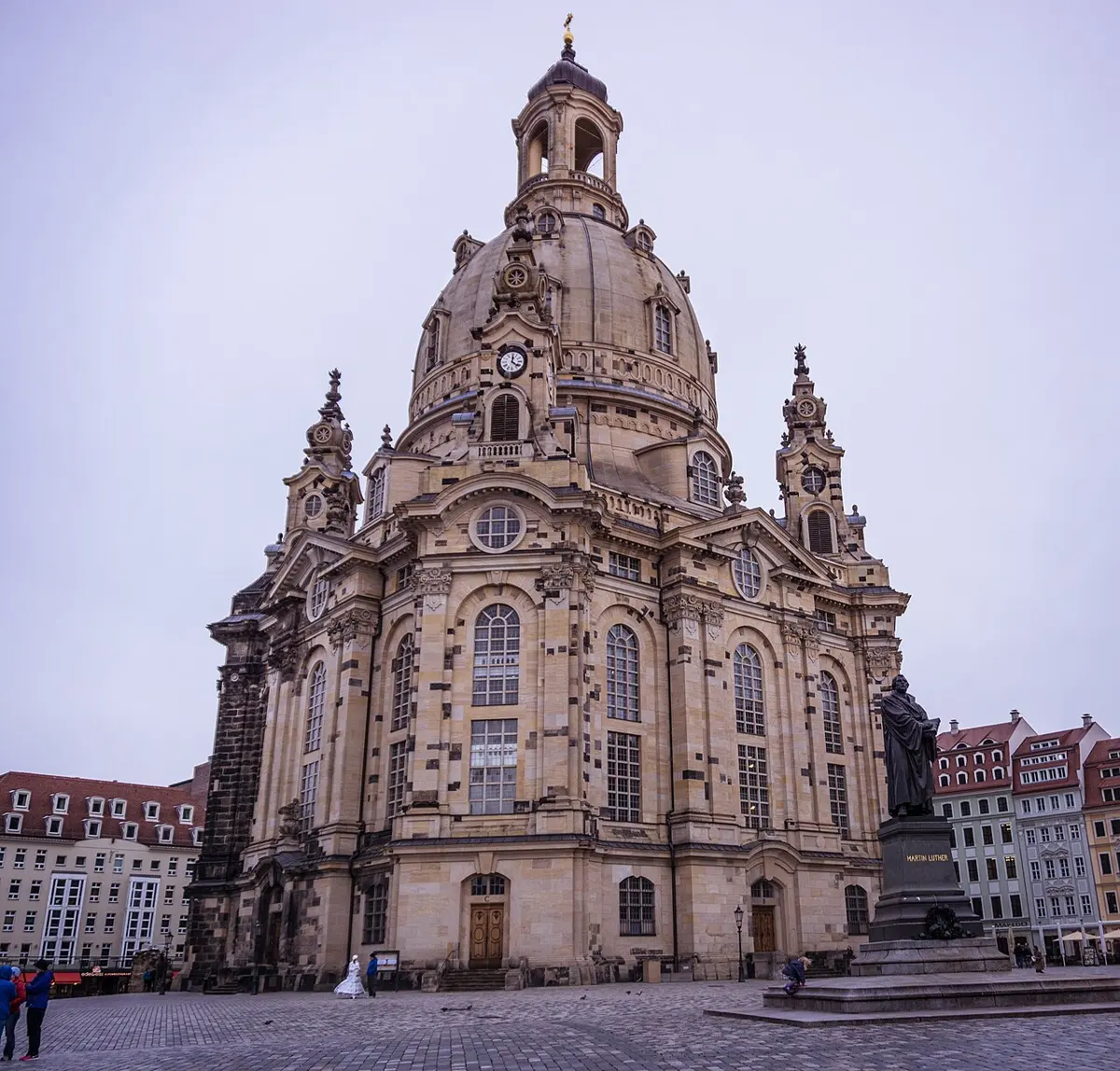 A tall pale stone church with a great bell-shaped dome, in a city square
