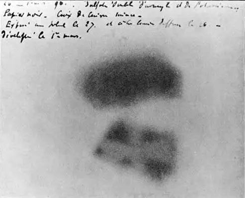 An old photographic plate with two dark, blurry patches, the lower one mottled, and four lines of handwriting in French along the top