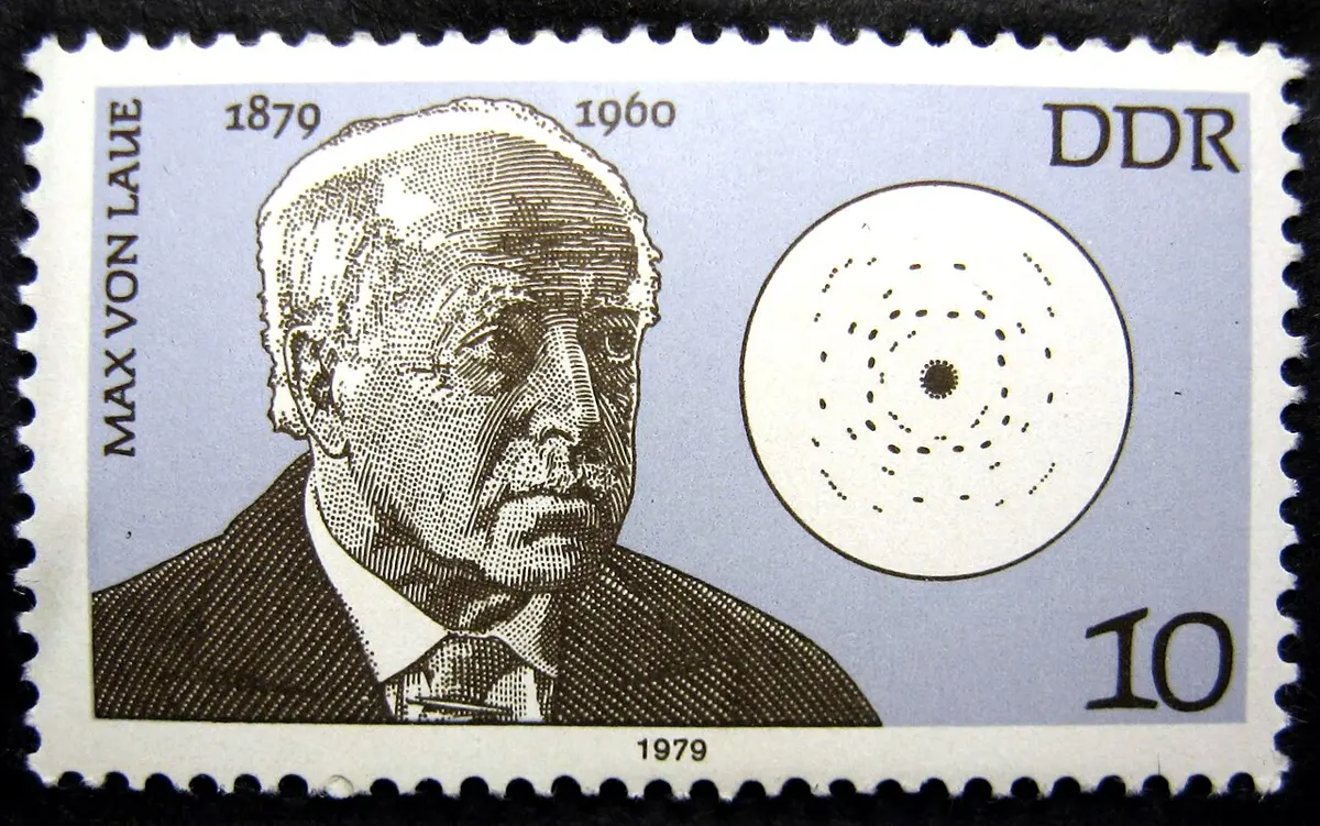 A postage stamp from East Germany, 1979: an engraved portrait of an old man, Max von Laue, labeled with the years 1879 and 1960, and beside him a white circle with a dark central spot surrounded by rings of small dots