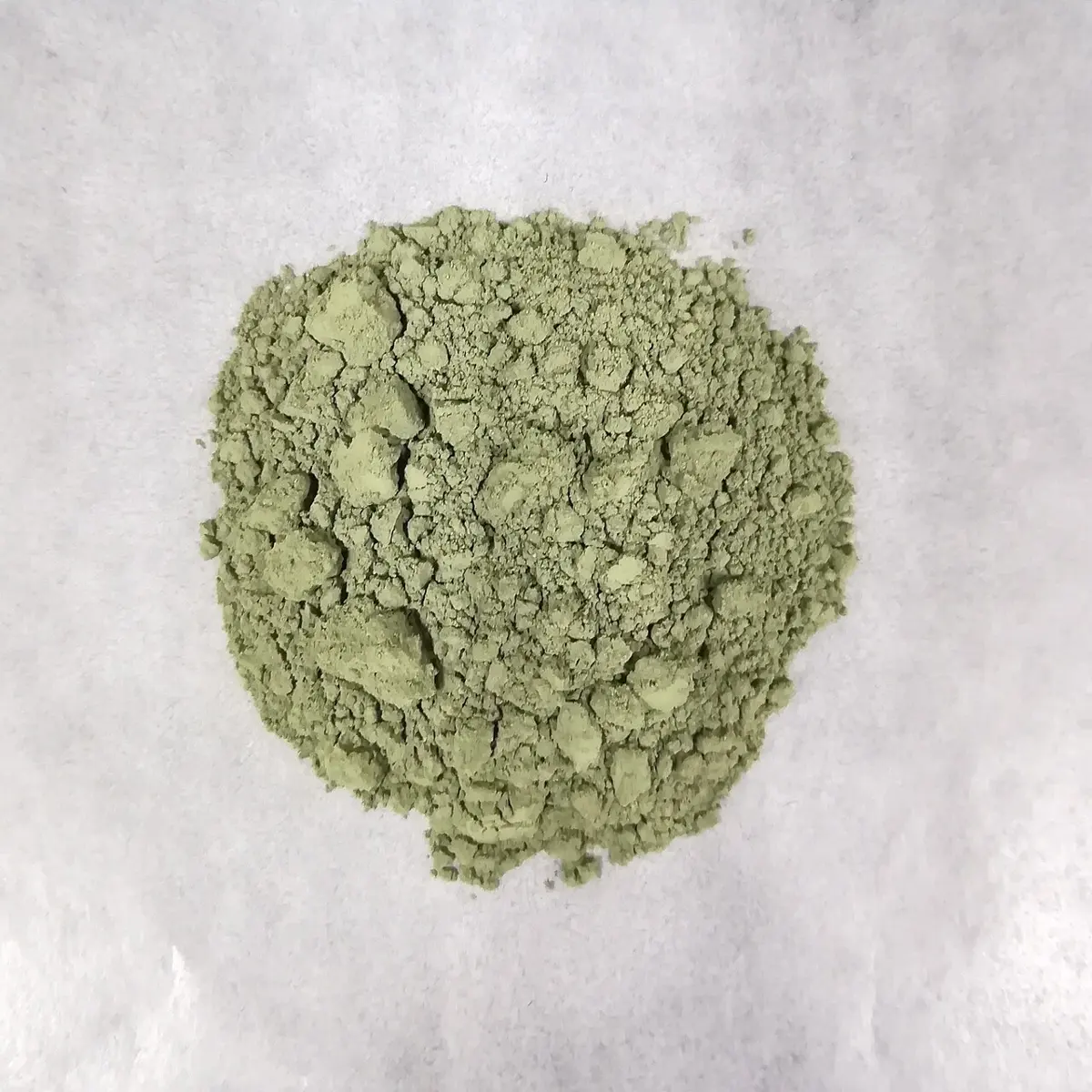 A small heap of fine, pale green powder on white paper