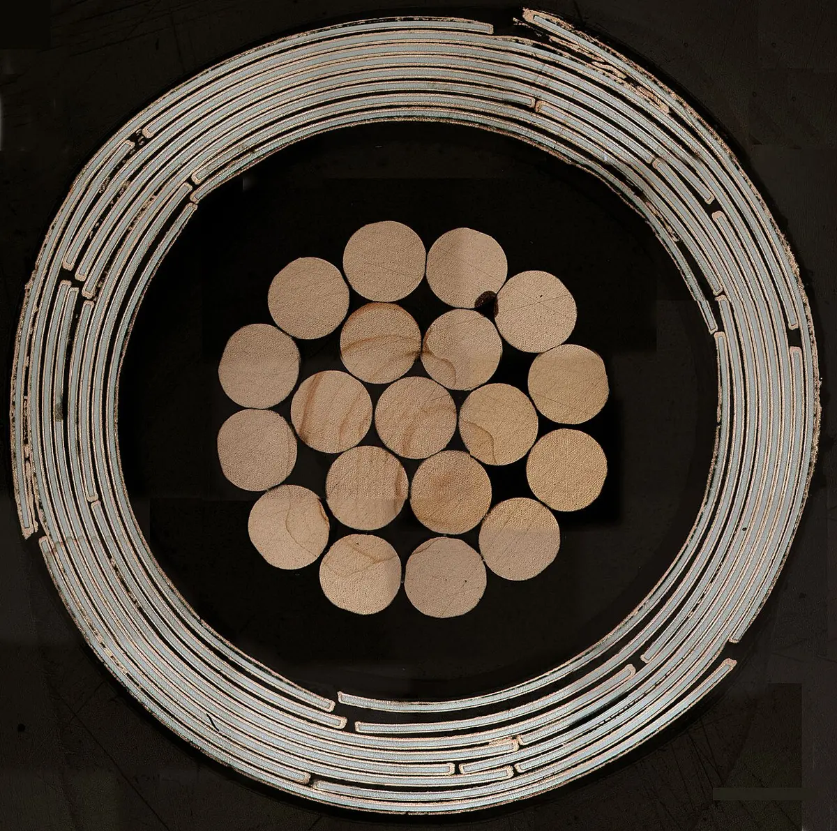 Cross-section of a round cable: a bundle of round copper wires in the middle, surrounded by thin spiraling rings of tape