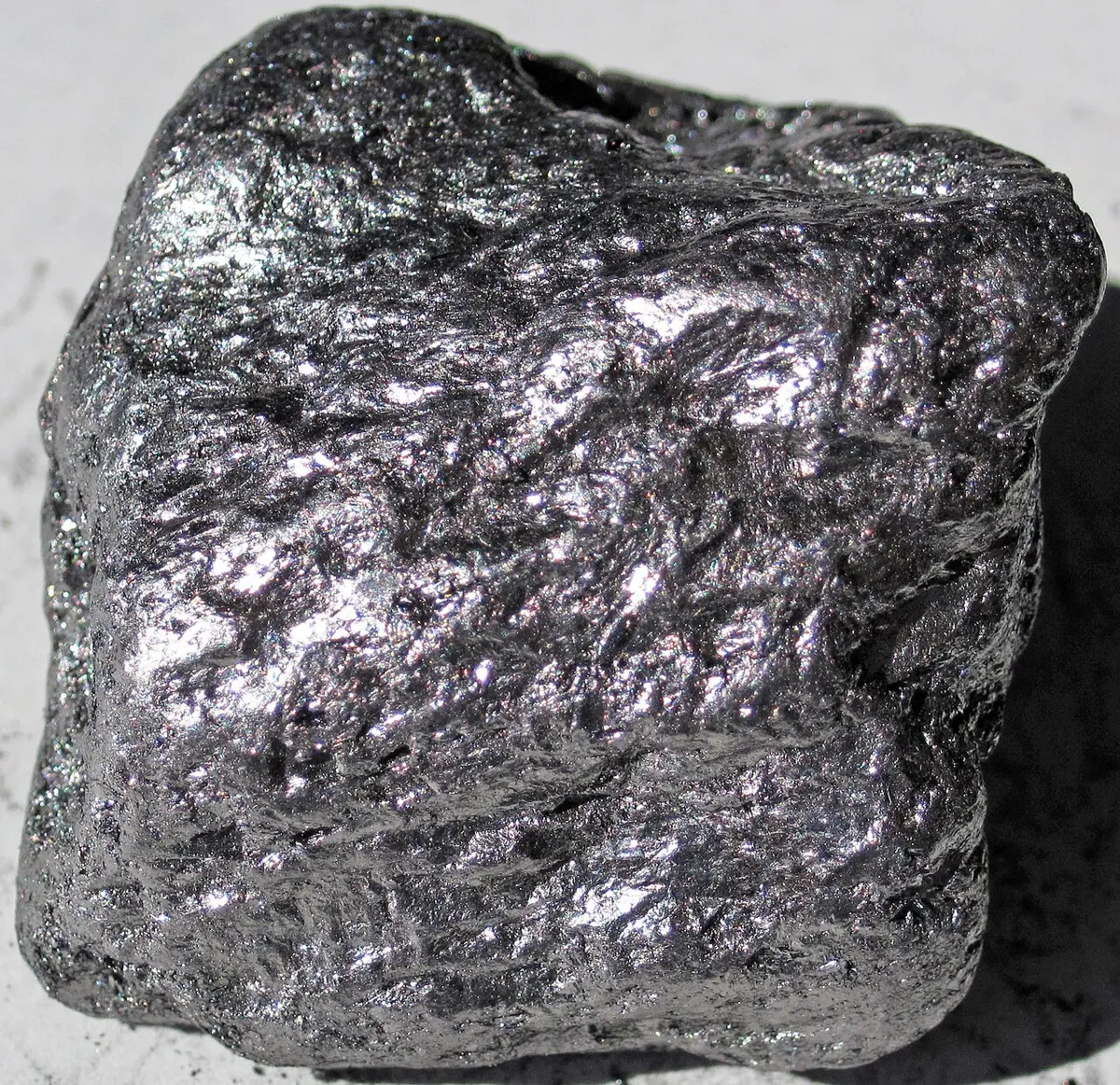 A lump of shiny, dark gray graphite with a flaky, metallic-looking surface