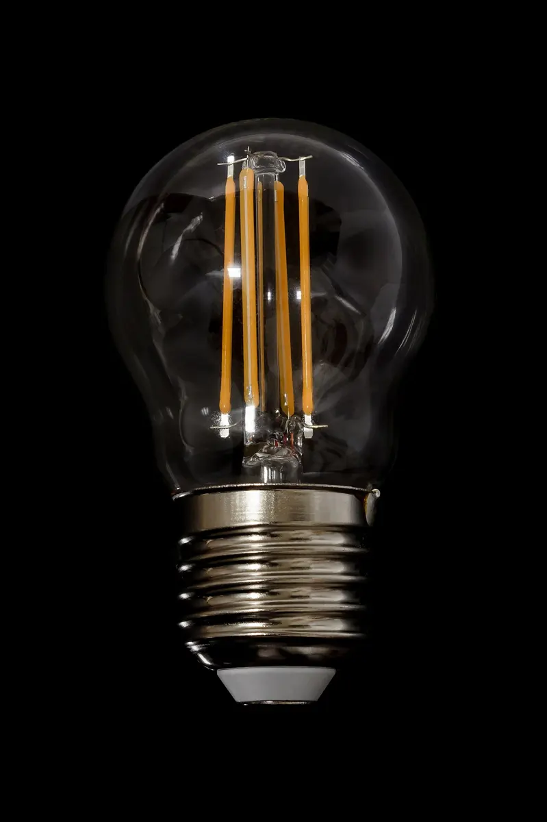 A clear glass bulb, lit, with thin glowing yellow strips inside instead of a single wire filament