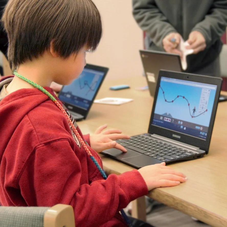 A student at a laptop running a PhET simulation of a roller coaster track
