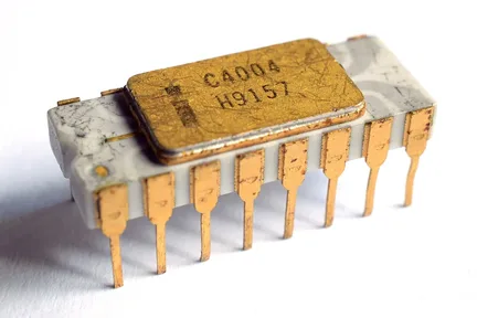 An Intel 4004 chip: a small white and gold rectangle with 16 metal legs