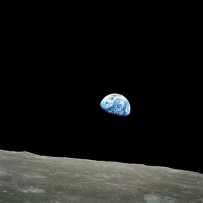 Earthrise: the Earth, half lit, rising above the gray horizon of the Moon