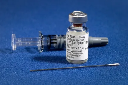 A smallpox vaccination kit: a small glass bottle of vaccine and a two-pronged needle