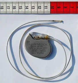 A modern pacemaker, about 4 cm long, beside a ruler